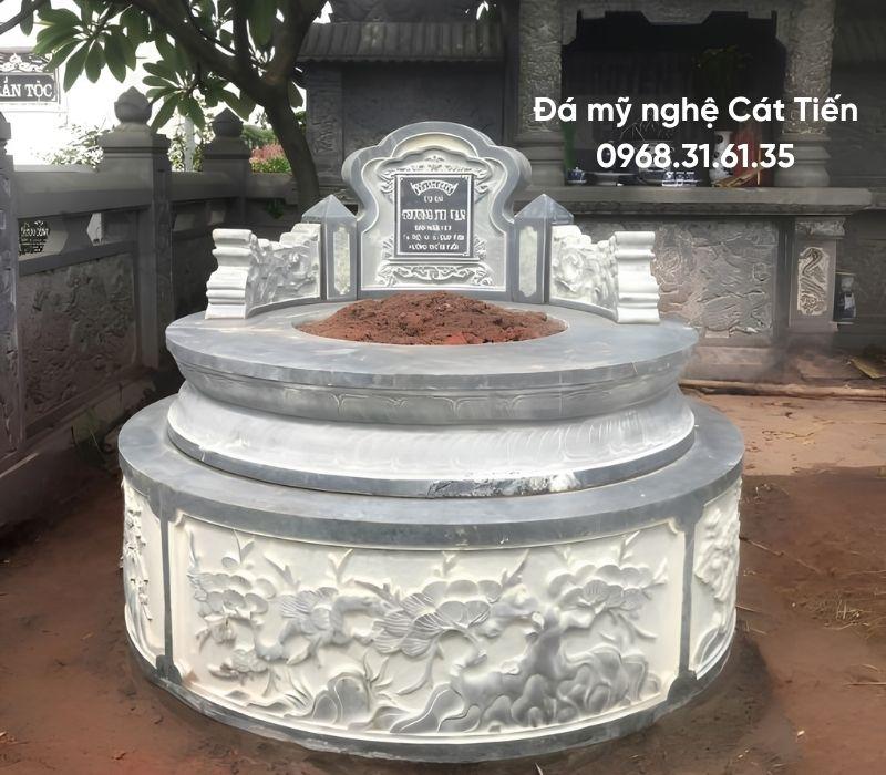 Mẫu mộ đá tròn trắng viền xanh đen chạm khắc cánh sen, tùng cúc trúc mai kích thước 127cm × 127cm giá 20 triệu.